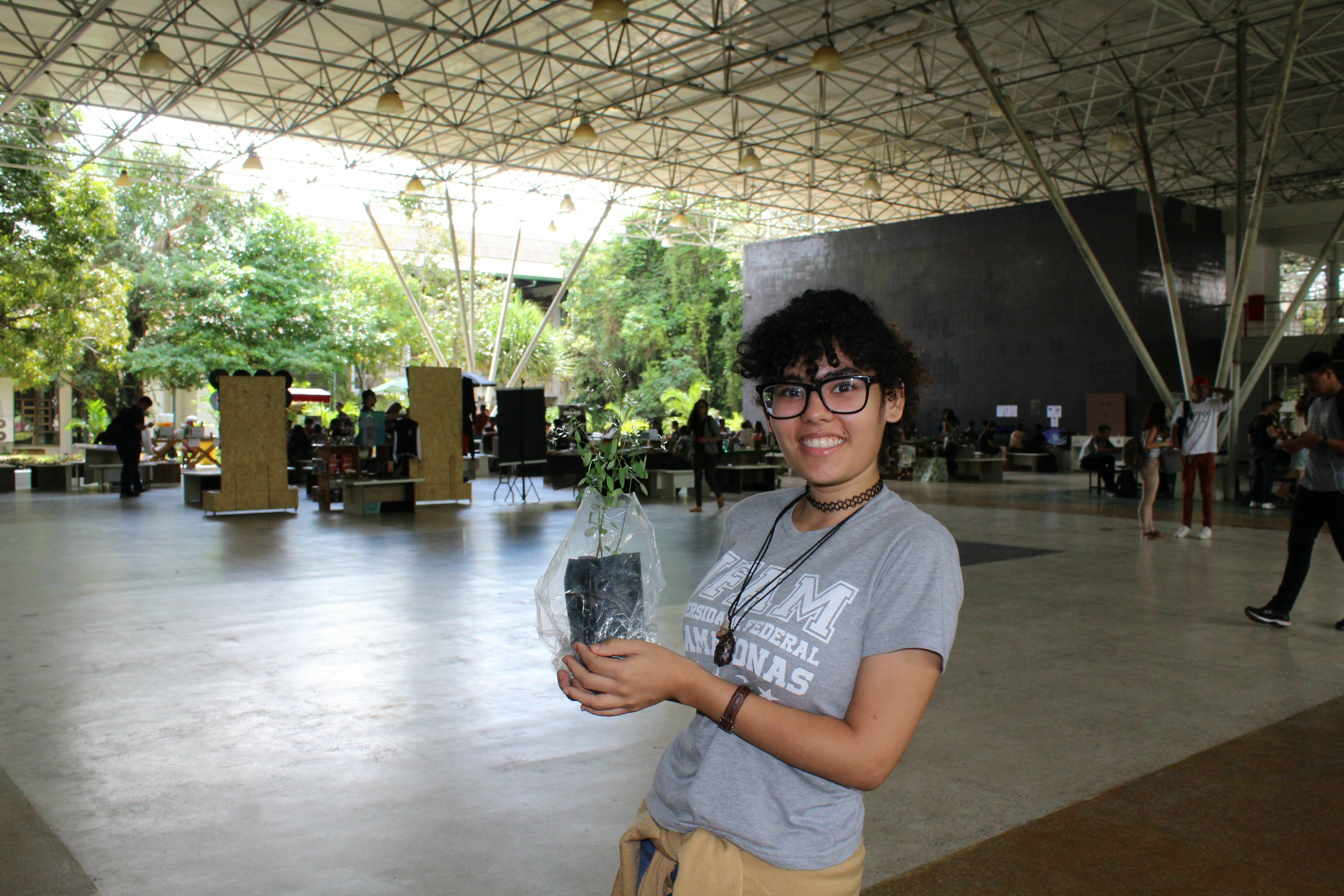 Distribuição de mudas - aluna do curso de Ciências Naturais, Karoline Prado, participou do evento e levou muda de "onze horas" para casa